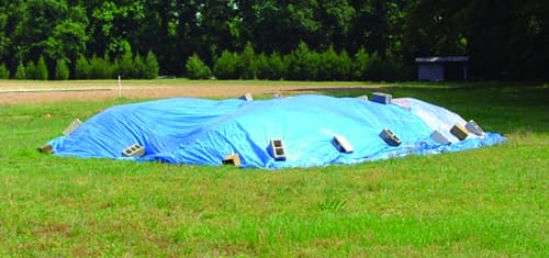 The simple use of a tarp to cover manures can help create drier conditions for manure storage. Photo Taken by Virginia Cooperative Extension. Image source: https://www.canr.msu.edu/news/storing_manure_on_small_farms_deciding_on_a_storage_option 